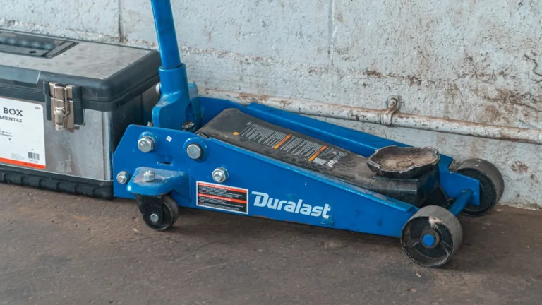 A blue hydraulic floor jack with a toolbox in an automotive garage setting — SSK Mechanics guide to Is It Safe to Book a Mobile Mechanic? Insurance,…