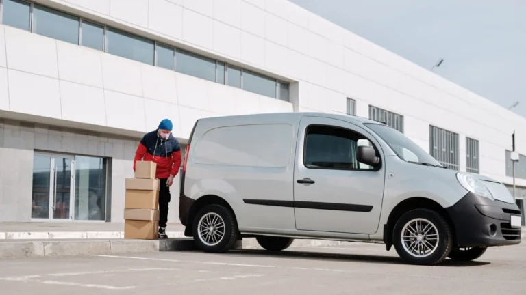 A delivery driver wearing a face mask unloads packages from a van outside a modern building — SSK Mechanics guide to The True Cost of a Van Off the Road: Downtime for Tradespeople