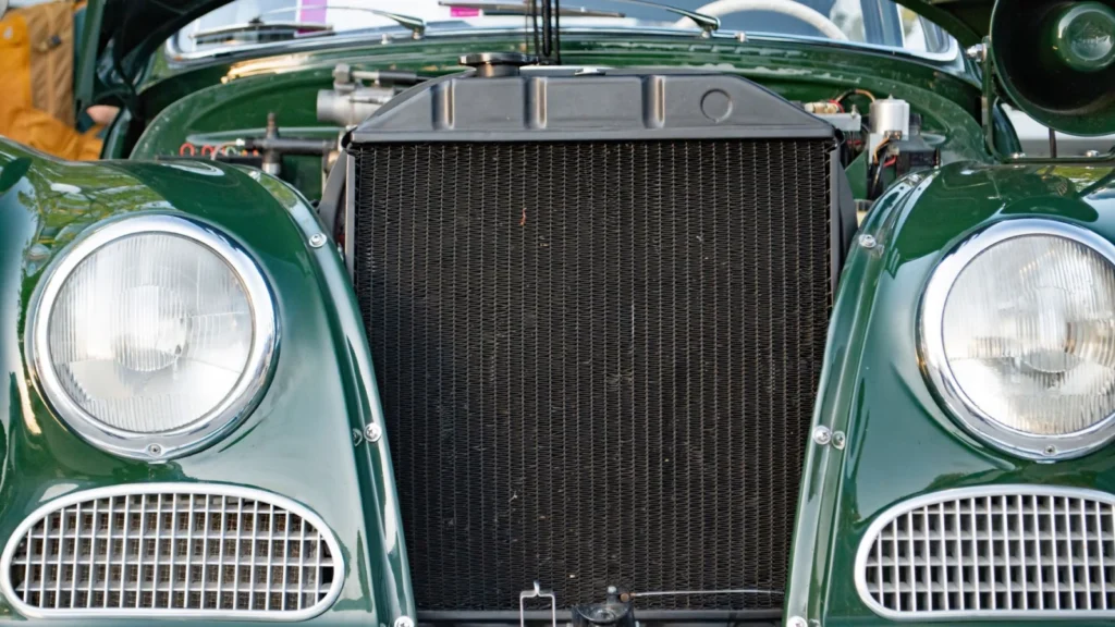 Close-up view of the radiator and headlights of a vintage green car in daylight — SSK Mechanics guide to Checking and Topping Up Your Car's Fluids: A Safe DIY Guide