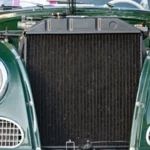 Close-up view of the radiator and headlights of a vintage green car in daylight — SSK Mechanics guide to Checking and Topping Up Your Car's Fluids: A Safe DIY Guide