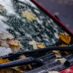 Close-up of wet car windshield with fall leaves, creating a moody autumn scene — SSK Mechanics guide to Wiper Blade Replacement: A Simple DIY Job