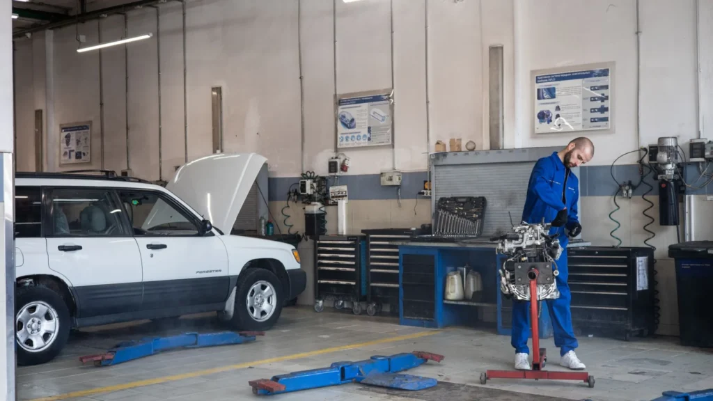 Mechanic in blue coveralls working on an engine in a modern auto repair workshop — SSK Mechanics guide to Why Brake Work Isn't a Safe DIY Job for Most Drivers