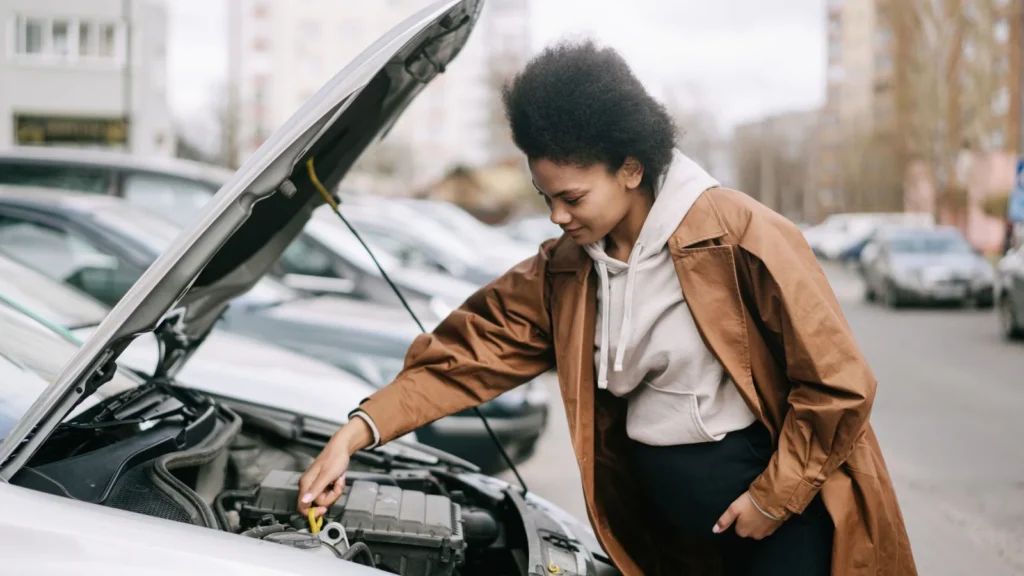 A pregnant woman inspects a car engine outdoors, showcasing independence and car maintenance skills — SSK Mechanics guide to Basic Under-Bonnet Checks Every Driver Can Do
