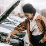 A pregnant woman inspects a car engine outdoors, showcasing independence and car maintenance skills — SSK Mechanics guide to Basic Under-Bonnet Checks Every Driver Can Do