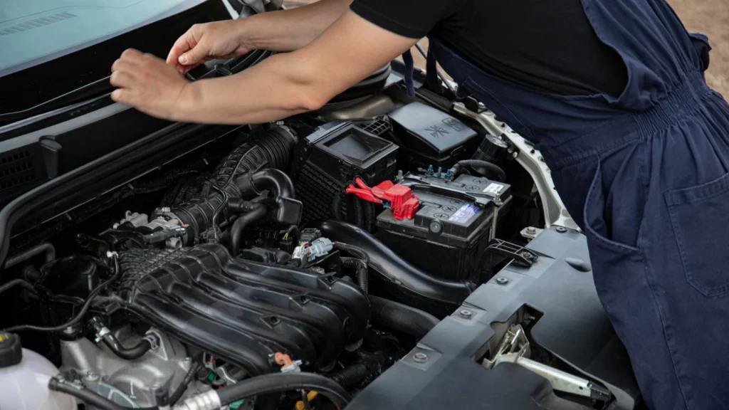 Mechanic performing maintenance on a car engine outdoors during the day — SSK Mechanics guide to Jump Start or New Battery? How to Tell Which Your Car Needs