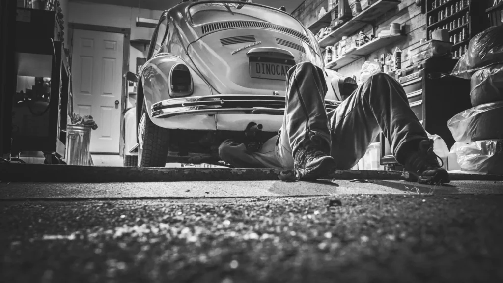 Mechanic working beneath a classic Volkswagen Beetle in a vintage garage setting — SSK Mechanics guide to SSK Mechanics vs ClickMechanic: How Mobile Mechanic Booking…