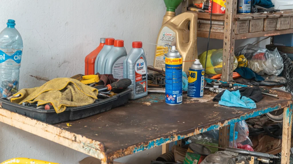 A cluttered workbench in an automobile garage with tools, oil cans, and maintenance products — SSK Mechanics guide to AA Mobile Servicing vs SSK Mechanics: Comparing Cost, Speed…