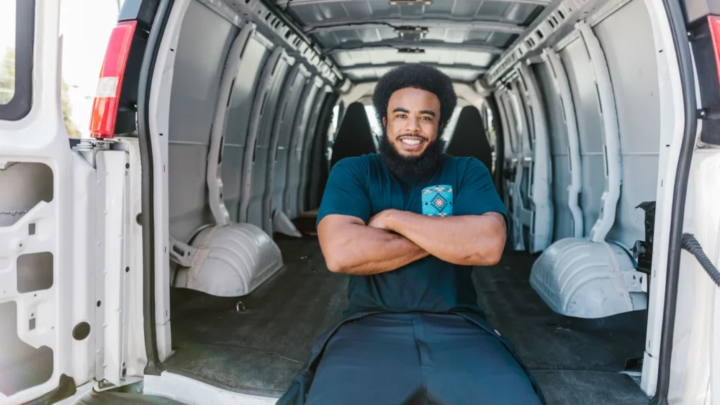 African American man with a beard sitting and smiling inside an empty van, showcasing relaxation… — SSK Mechanics guide to AA Business Breakdown Cover vs Scheduled Mobile Fleet Maintenance