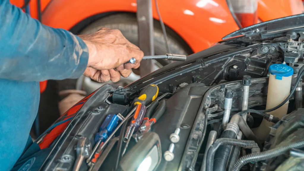 Mechanic performing maintenance on a car engine in a garage setting, using various tools — SSK Mechanics guide to ClickMechanic Leeds vs SSK Mechanics: Coverage and Response…