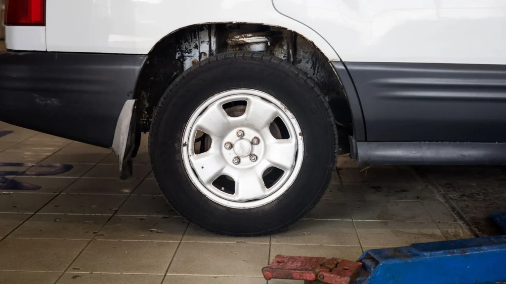 Detailed view of a car wheel in an auto repair shop setting with a hydraulic jack — SSK Mechanics guide to ATS Euromaster MOT vs a Local MOT Centre: Comparing Price and…