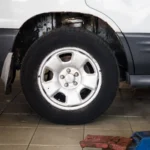 Detailed view of a car wheel in an auto repair shop setting with a hydraulic jack — SSK Mechanics guide to ATS Euromaster MOT vs a Local MOT Centre: Comparing Price and…