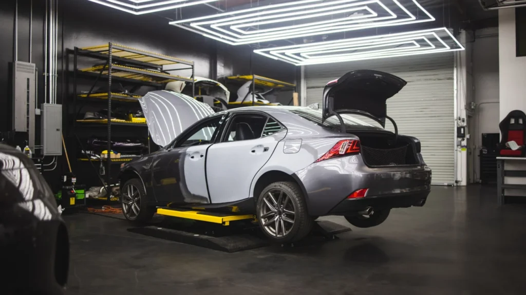Gray car undergoing repairs in a sleek, modern auto repair shop environment — SSK Mechanics guide to AA/RAC Repair Cost vs a Local Mobile Mechanic: What…