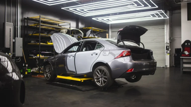 Gray car undergoing repairs in a sleek, modern auto repair shop environment — SSK Mechanics guide to AA/RAC Repair Cost vs a Local Mobile Mechanic: What…