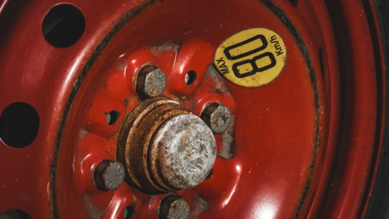 Detailed view of a rusty red spare car wheel with an '80 KM/H' max speed warning label — SSK Mechanics guide to Kwik Fit MOT Advisories vs a Second Opinion: Why It's Worth…
