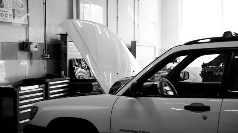 Black and white photo of a car in an auto repair shop. Hood open for maintenance — SSK Mechanics guide to Halfords vs Kwik Fit MOT: Which Is Better for Bradford Drivers