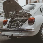 Old-fashioned vintage car with open engine hood on a city street in Curitiba, Brazil — SSK Mechanics guide to ClickMechanic Car Inspection vs SSK Mechanics: Comparing…