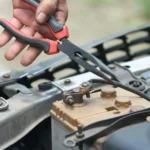 Person using pliers to check a car battery in an outdoor setting — SSK Mechanics guide to Kwik Fit EV Battery Health Checks vs a Full Mobile Diagnostic