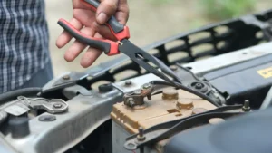 Person using pliers to check a car battery in an outdoor setting — SSK Mechanics guide to Kwik Fit EV Battery Health Checks vs a Full Mobile Diagnostic
