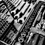 Close-up black and white photo of a complete wrench and socket tool set within a toolbox — SSK Mechanics guide to Halfords DIY Parts Counter vs Professional Fitting: What's…